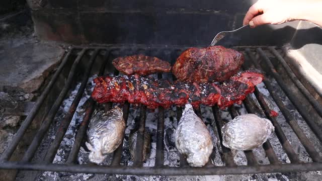 把烧烤排骨、猪肉和土豆放在木头和木炭烤架上视频素材