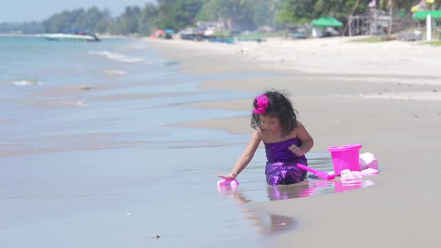 4K亚洲家庭假期快乐。可爱的小女孩穿着美人鱼泳衣坐在沙滩上玩沙滩玩具。可爱的孩子女孩放松和有乐趣的夏季旅行旅行。视频下载