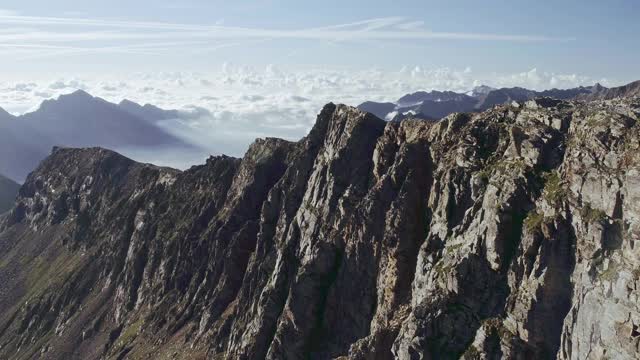 鸟瞰图的岩石山悬崖。美丽的风景在背景，云覆盖较低的山峰在一个阳光明媚的夏日视频素材