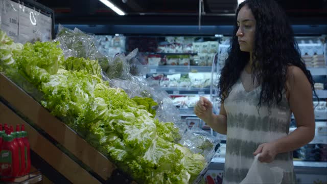 女人在超市买东西，买食物，在市场上挑选西红柿，在超市里。购买。股票视频视频素材