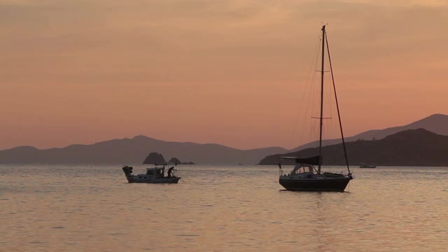 独自在夕阳下航行。大气海景与橙色的太阳。视频素材