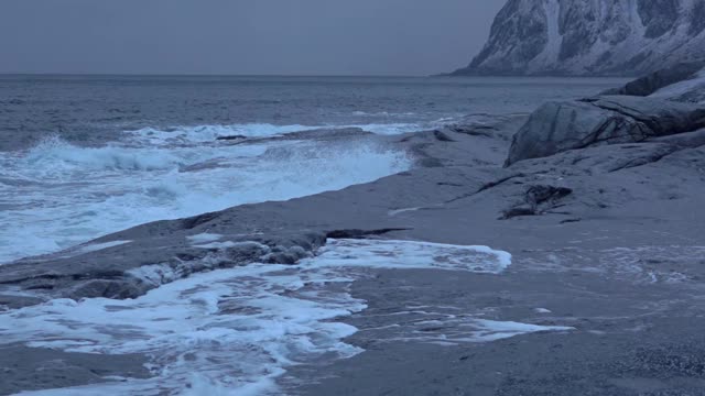 冬季傍晚在石滩上冲浪。慢动作视频素材