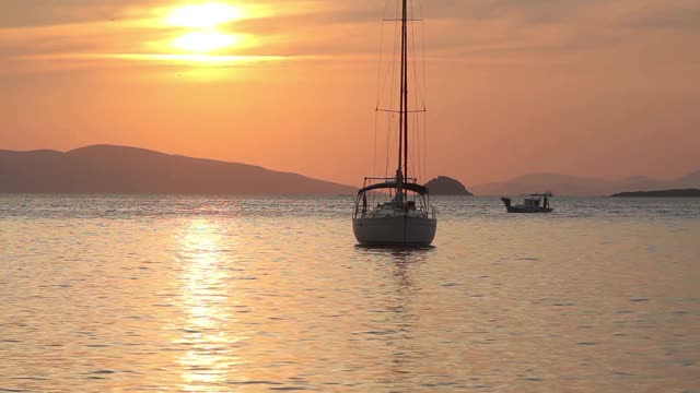 独自在夕阳下航行。大气海景与橙色的太阳。视频素材