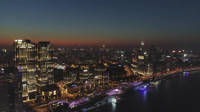 照亮上海城市夜景。浦西和黄浦江。鸟瞰图。无人机向后飞行。视频素材