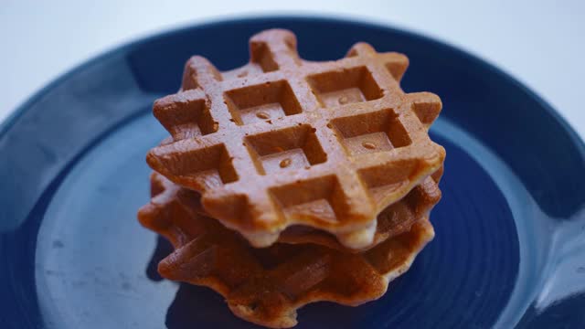 在早午餐时把枫糖浆倒在金黄色的华夫饼上。特写镜头。视频素材