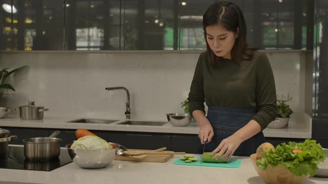 甜蜜的亚洲夫妇在现代化的厨房里一起烹饪晚餐，享受为对方提供食物和准备健康的沙拉食物的配料。生活方式奢侈舒适。爱，幸福家庭理念。视频素材