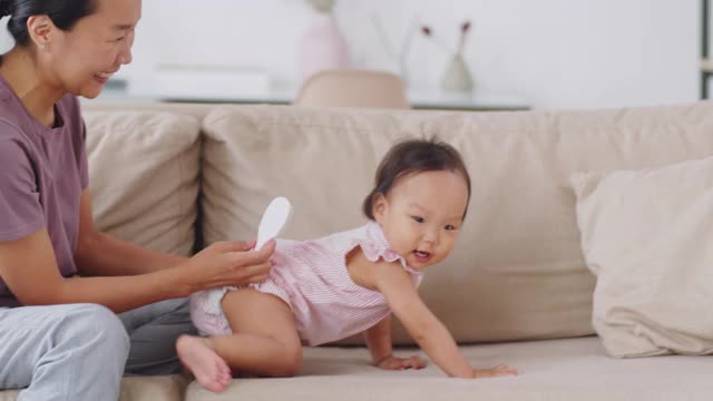 亚洲妈妈在家里给女婴梳头视频素材