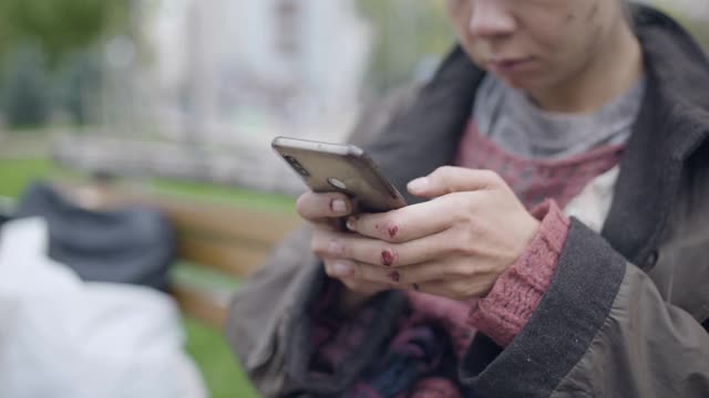 贫穷的年轻女性在户外用智能手机打字，城市无家可归视频素材