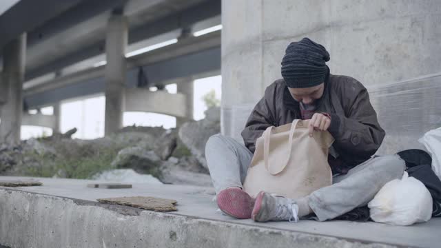 绝望的女流浪汉咬着面包，在街上生存，经济危机视频素材