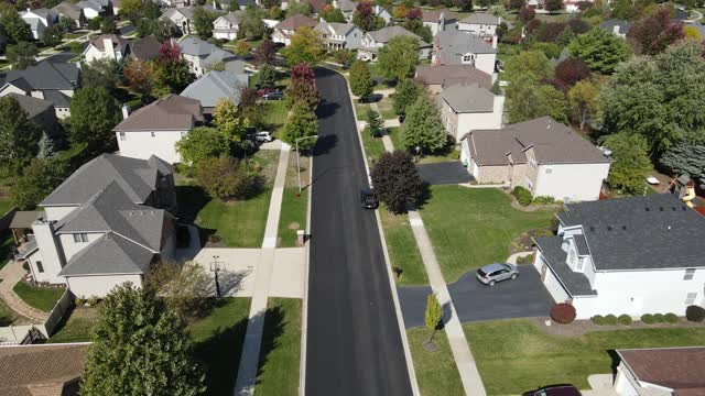 在芝加哥地区沿着郊区街道的彩色秋树、住宅和庭院的高空鸟瞰图。美国中西部。4 k视频下载