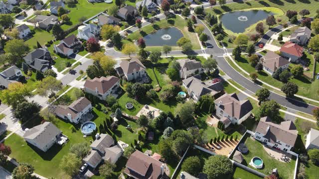 头顶鸟瞰图多彩的秋天的树，住宅和院子排水池塘沿郊区街道在芝加哥地区。美国中西部。4 k视频下载