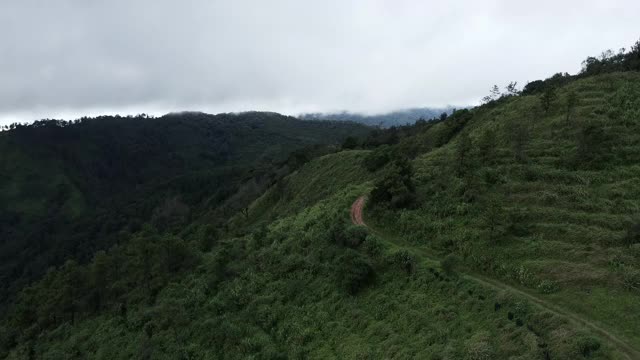 无人机航拍景观山脉与森林土路在上午阴天。全景绿色森林与风吹雾海通过山峰在泰国清迈视频下载
