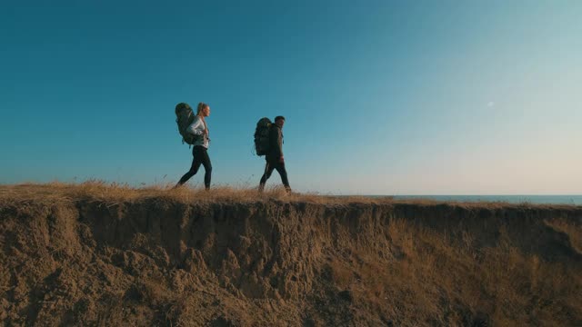 在夕阳的背景下，这对夫妇在山上散步视频素材