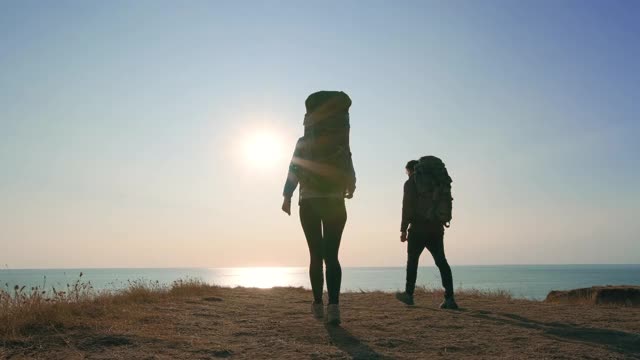 男人和女人在夕阳的背景下走在山上视频素材