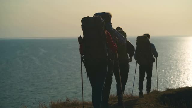 四个徒步者在夕阳的映衬下走在山上视频素材