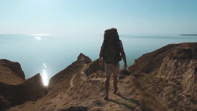 在海边岩石上行走的徒步旅行者。慢动作视频素材