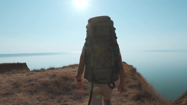 背靠大海在山上行走的徒步旅行者。慢动作视频素材