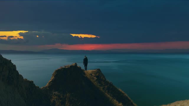 背包男子站在山腰上，背景是海景视频素材