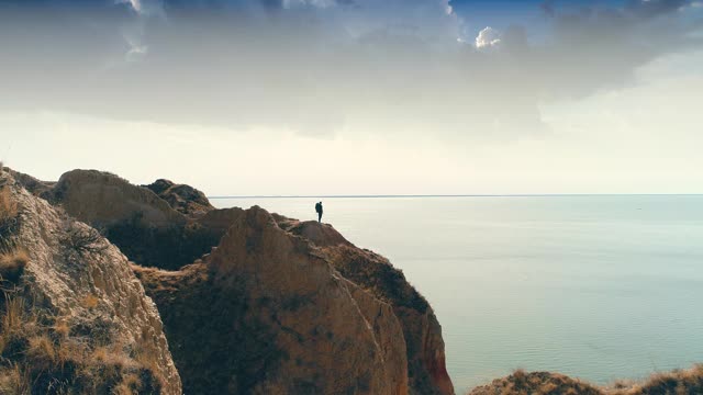 游客站在山的边缘，背景是海景视频素材