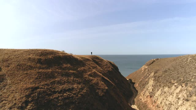 那个拿包的人站在山顶，背对着海景视频素材