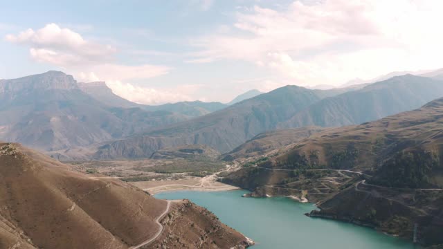 鸟瞰蜿蜒的山路和碧绿的湖水。美丽的吉日吉特山景。无人机飞过巴尔卡里亚Kabardino的Bylym村。视频素材