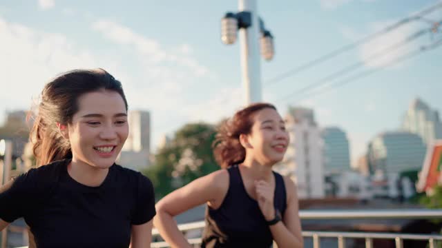 两名亚洲女性在公园边慢跑边看她的智能手表视频素材