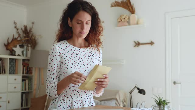 女人打开信封，取出信，读着可怕的消息视频素材