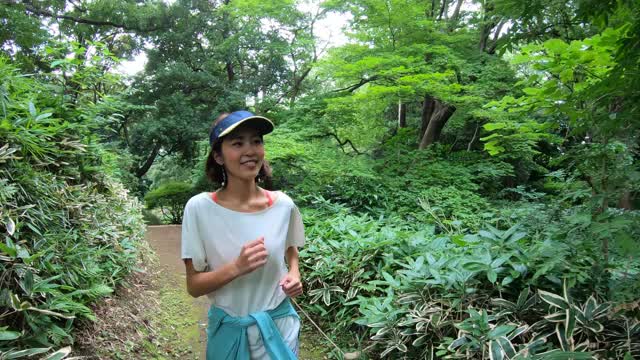 亚洲妇女跑步，慢跑，在城市公园做体育活动视频素材