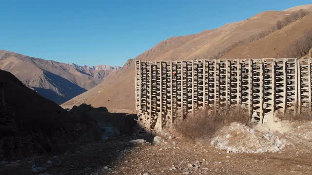 鸟瞰图铁混凝土保护结构从泥石流和雪崩。防护结构部分损坏。穿橙色夹克的人在没有保险的情况下爬到高空视频素材