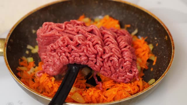 在煎锅里炸肉末、洋葱和胡萝卜。波伦亚的酱视频素材