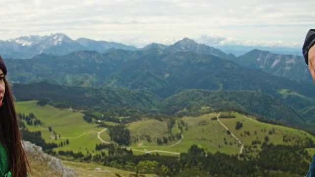 一名男子帮助年轻的徒步旅行者到达山顶视频素材