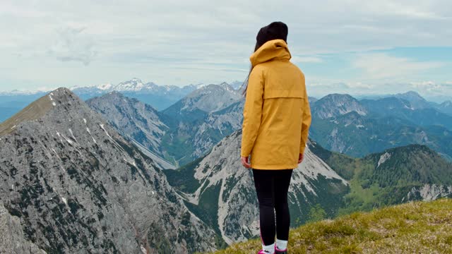 一个年轻的徒步旅行者在山顶张开双臂视频素材