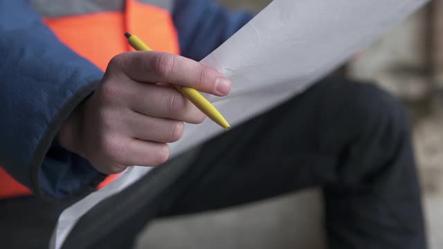 一位年轻的男建筑建筑师正在检查建筑的施工情况。工程师在高层建筑工地检查图纸。视频素材