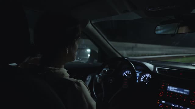 这个女人晚上在高速公路上开车。视频素材