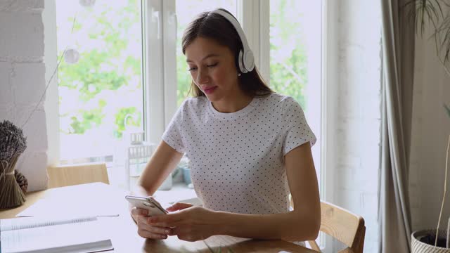 快乐的年轻女子戴着耳机兴奋的好消息消息。视频素材