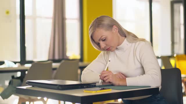 白种年轻女子使用平板电脑和数字笔检查手机上的信息。这个女孩因为这个悲伤的消息而心烦意乱。来自办公室的信息干扰了工作。视频素材