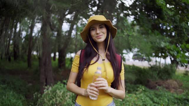 女性白种人喝水后旅行的野生冒险在森林假日。视频素材