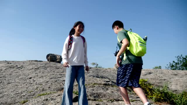 亚洲儿童背包客在阳光明媚的日子里一起登山，户外探险的概念。视频素材