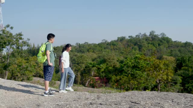 亚洲儿童背包客在阳光明媚的日子里一起登山，户外探险的概念。视频素材