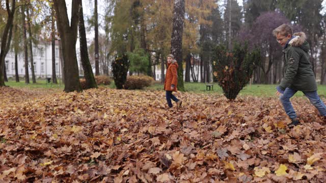 男孩们在公园里踢秋叶视频素材