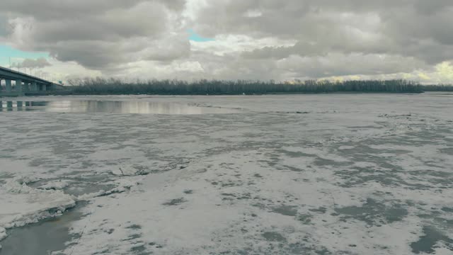 河岸上冻得很深的河流，地平线上有茂密的森林视频素材