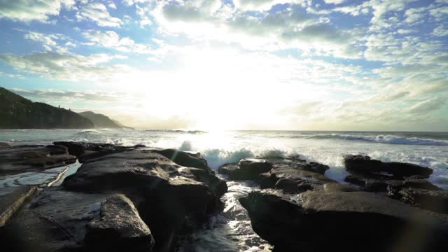 倾斜下来:海浪拍打岩石与人在海滩上的天空-卧龙岗，澳大利亚视频素材