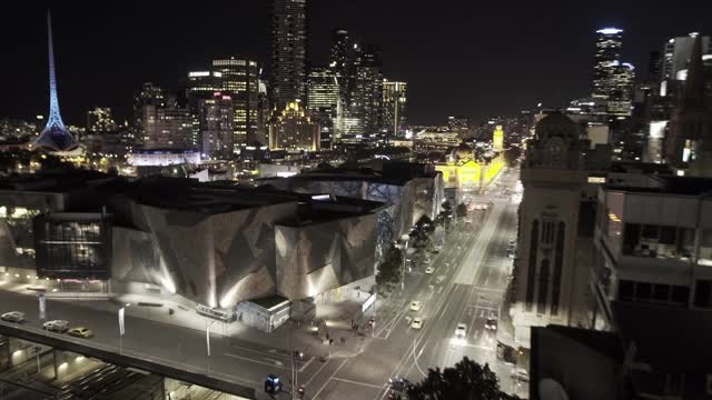 澳大利亚墨尔本:夜间城市大楼间街道上的车辆视频素材