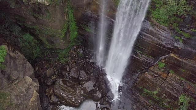 空中封锁:澳大利亚贝尔莫瀑布在森林里的岩石上飞溅视频素材