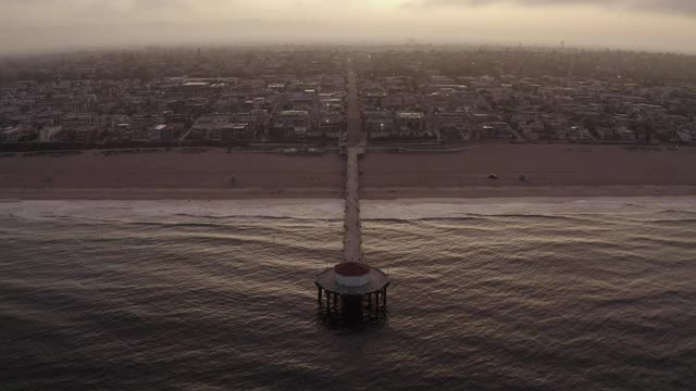 空中向后:日出时在海滨城市的海滩码头-曼哈顿海滩，加利福尼亚视频素材