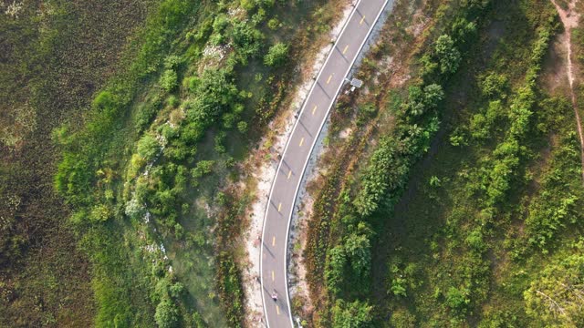 鸟瞰图骑自行车的人沿着乡村道路。无人机飞行拍摄视频素材