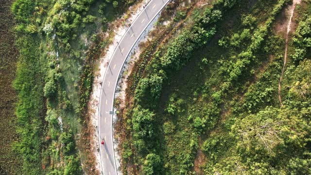 鸟瞰图骑自行车的人沿着乡村道路。无人机飞行拍摄视频素材