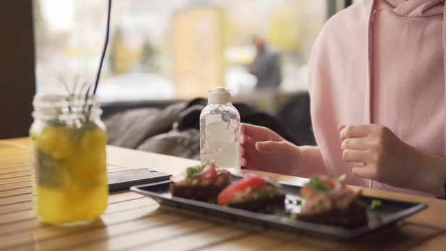 一名妇女在餐厅用餐前使用消毒剂消毒凝胶以保持卫生视频素材