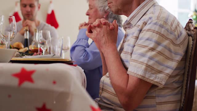 白种人家庭在午餐前坐在餐桌上一起祈祷视频素材