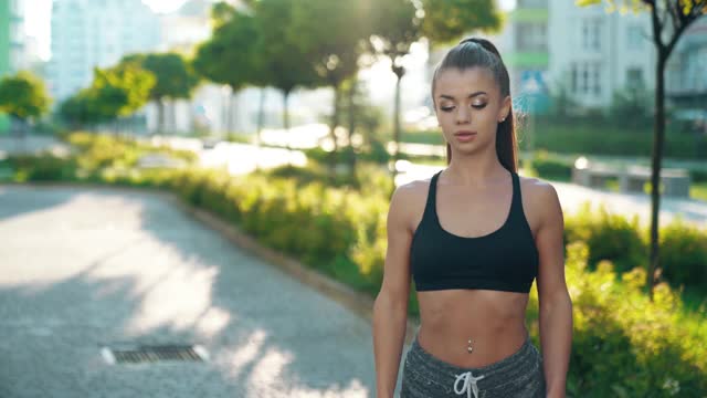 年轻女子在多层建筑附近热身。视频素材